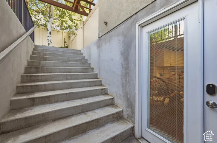 Concrete staircase with a metal handrail and a white door with integrated blinds