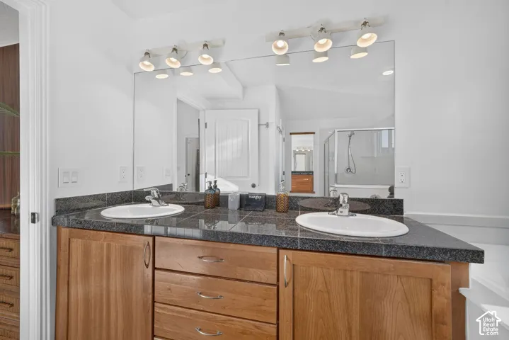 Dual vanity with wood-finish cabinetry, dark countertop, and integrated sinks