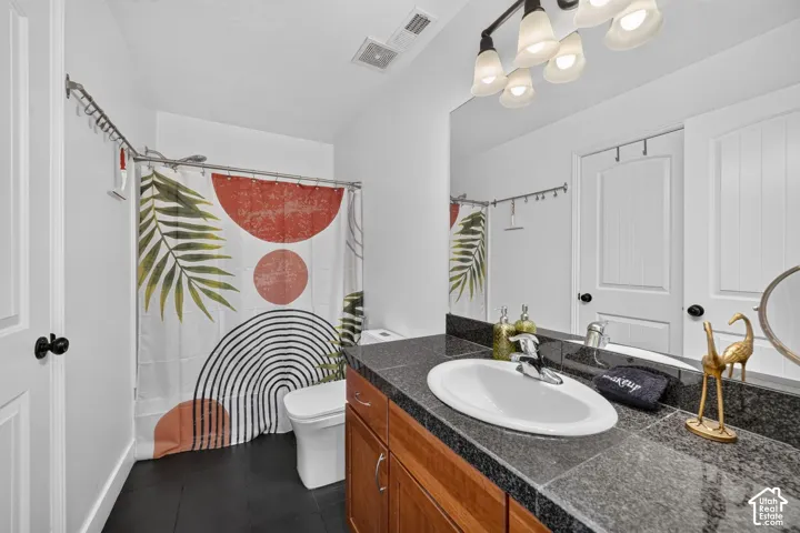Vanity with undermount sink and dark countertop, wood-finish cabinetry, and overhead sconce lighting