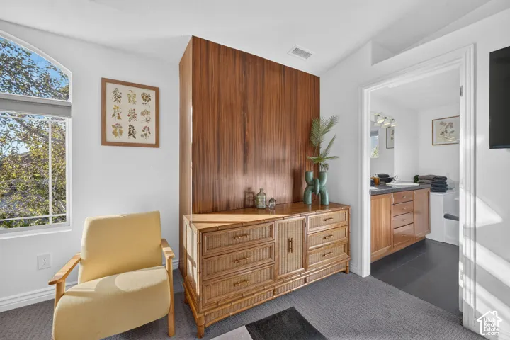 Arched window, wood accent wall, carpeting, recessed lighting, and an adjacent bathroom with a wood vanity