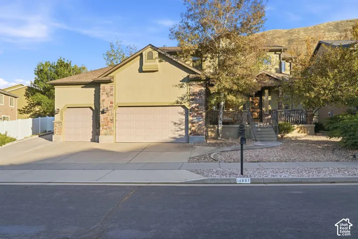 Stucco exterior with stone accents, covered front porch, and a two-car garage with an additional single-car garage