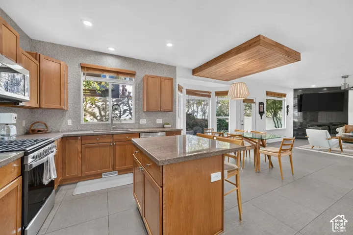 Expansive kitchen featuring wood cabinetry, stainless steel appliances, and a central island with countertop