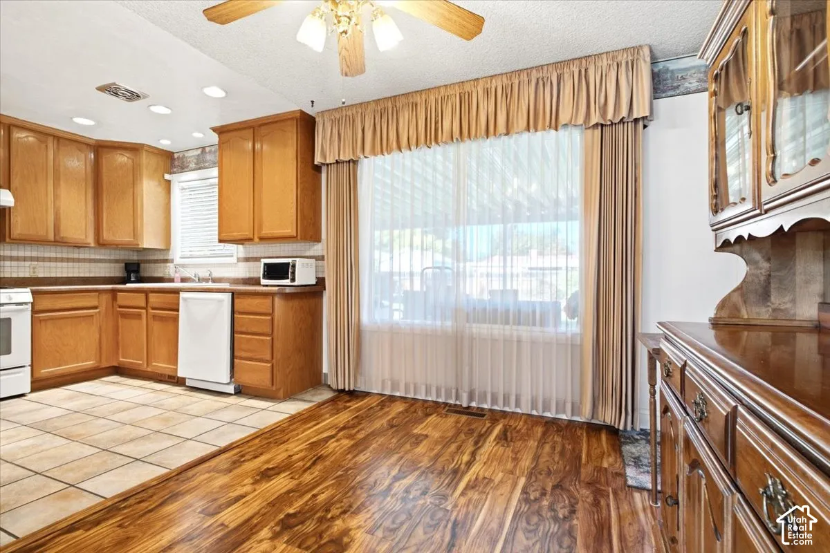 Kitchen area featuring wood cabinetry, white appliances, and recessed lighting