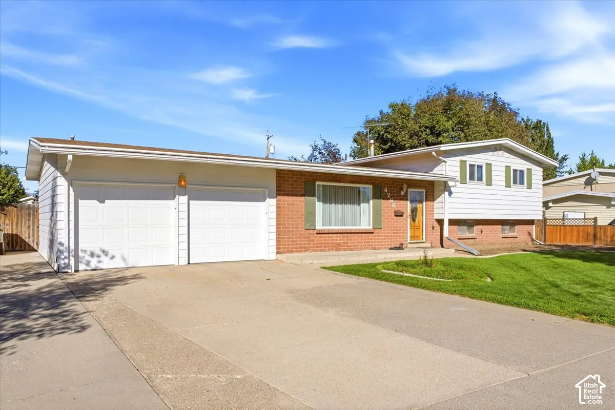 Red brick and white siding exterior with green window shutters, a two-car garage, and a concrete driveway