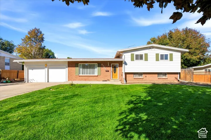 Red brick and white siding exterior with green shutters, two-car garage, and a concrete driveway