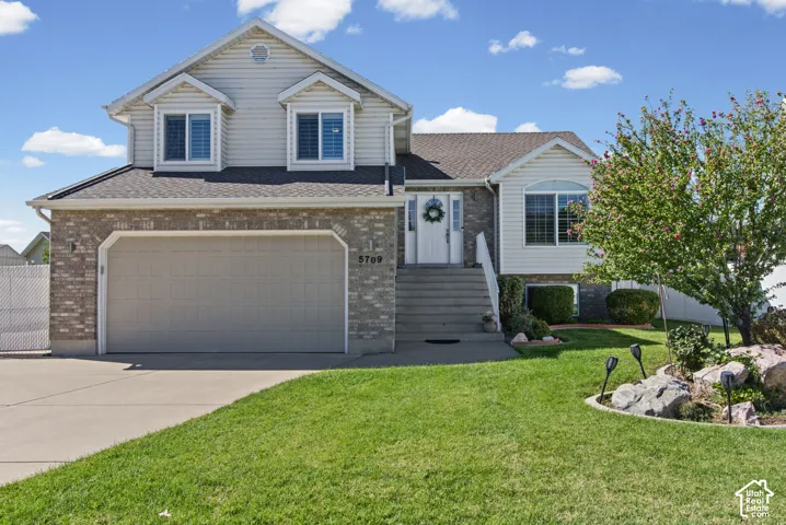 Tri-level residence featuring light brick and siding exterior, an attached two-car garage, and a concrete driveway