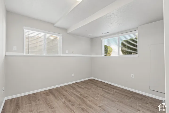 Wood-finish flooring, white walls, and two horizontal windows with blinds