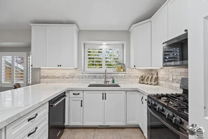 White shaker-style cabinetry with dark hardware, solid surface countertops, and an undermount sink