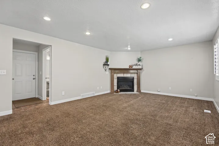 Recessed lighting, carpeting, and a fireplace with a wood mantel