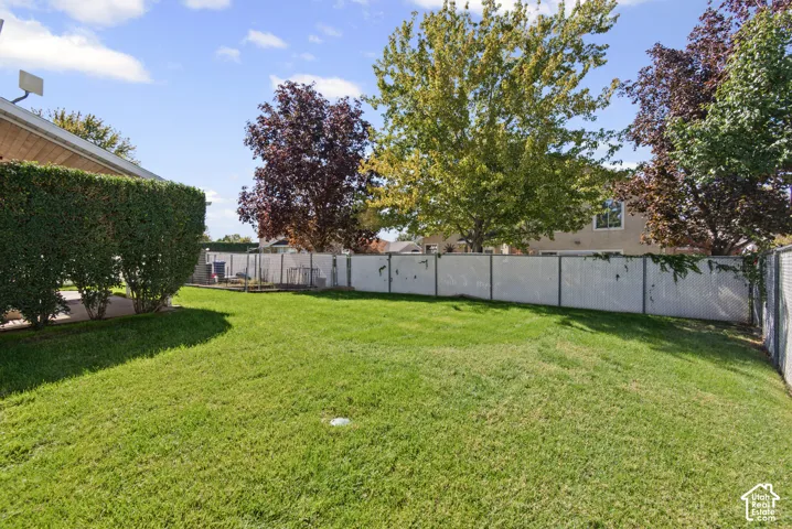 Expansive lawn with mature landscaping, privacy fencing, and established trees