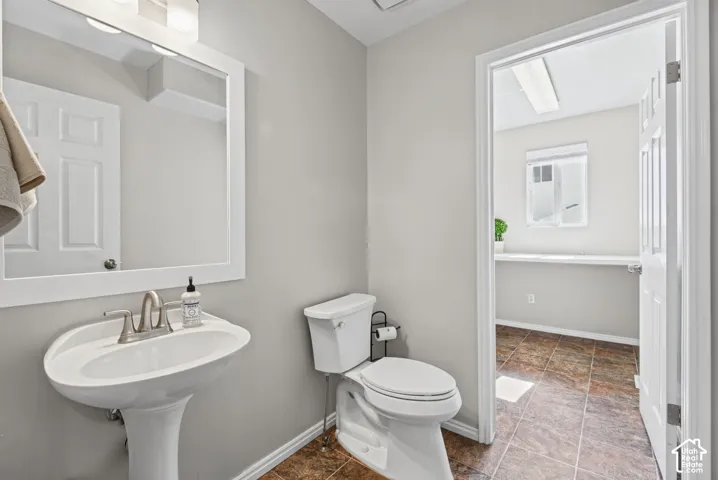 Pedestal sink with brushed nickel faucet, framed mirror, and two-bulb vanity light fixture