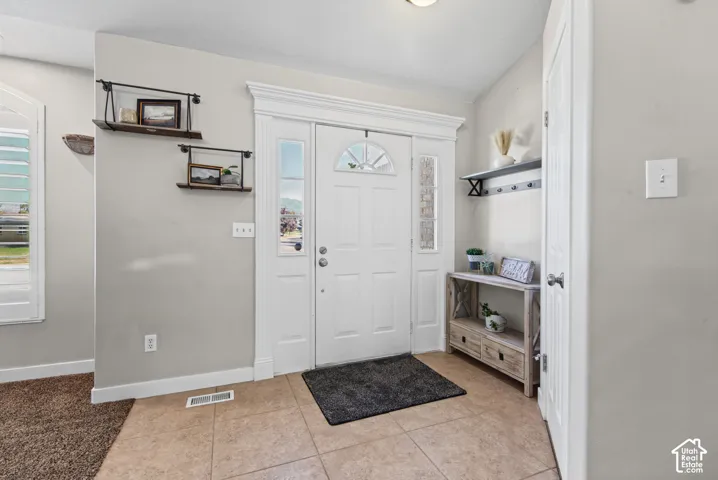 Entryway featuring a white door with transom and sidelights, tile flooring, and wall-mounted shelving