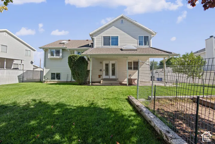 Expansive backyard featuring a covered patio, double French doors, skylight, and fenced garden or chicken area