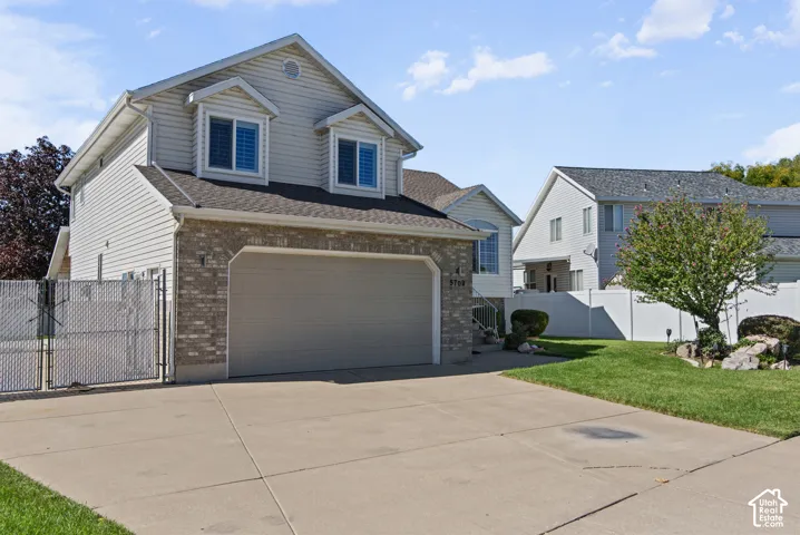 Tri-level residence featuring siding and brick facade, an attached garage, and a concrete driveway