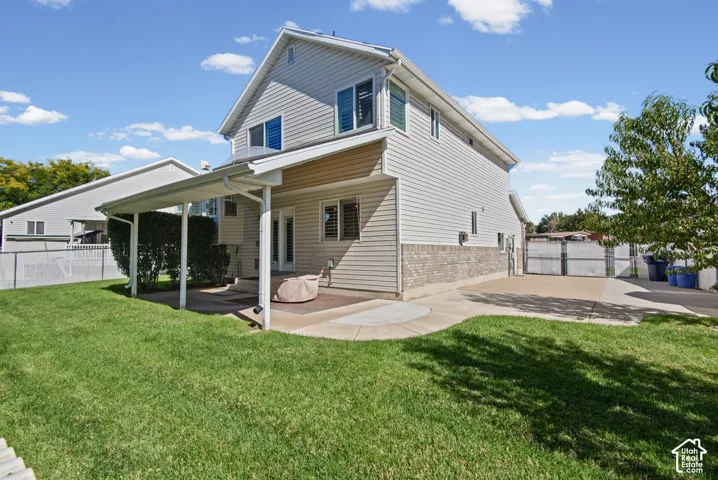 Expansive backyard featuring a covered patio, concrete patio, and a manicured lawn