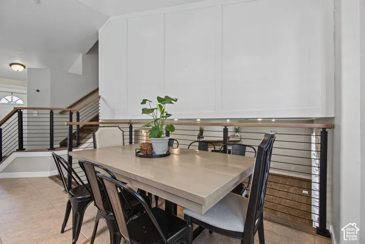 Tiled flooring, board and batten wall detailing, stairwell with wood handrail, black metal balusters, and a semi-flush mount ceiling fixture