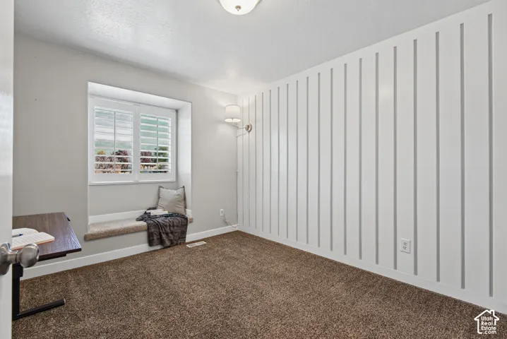 Window with plantation shutters, integrated window bench, textured wall paneling, and wall-mounted light fixture