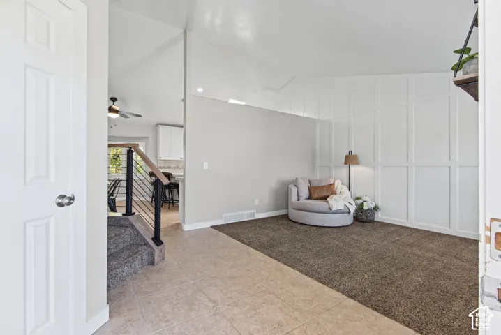 Vaulted ceiling with recessed lighting, white board and batten accent wall, neutral paint palette, tiled entry flooring, and modern staircase with wood-finish handrail and metal spindles