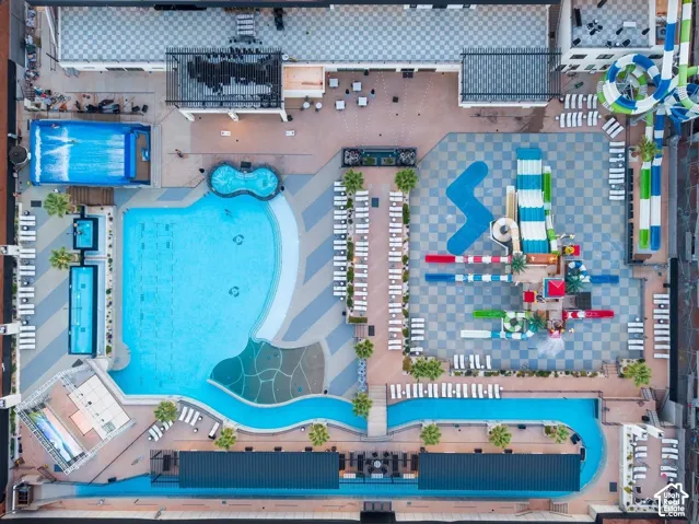 Expansive aquatic recreation area featuring multiple swimming pools and hot tubs, a lazy river, water slides, and a checkerboard paver deck