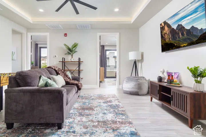 Recessed lighting in a tray ceiling, wood-finish flooring, and a wall-mounted display