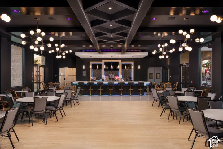 Expansive recreational space featuring a full-service bar, coffered ceiling, and light wood-finish flooring