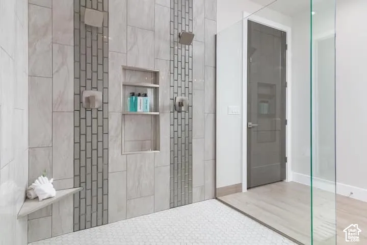 Walk-in shower with dual shower heads, mosaic tile accents, a recessed niche, and a corner bench