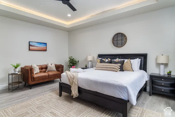 Tray ceiling with recessed lighting and a ceiling fan, light wood-finish flooring, and light wall tones