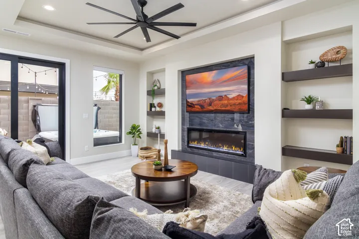 Recessed lighting, tray ceiling, and a modern ceiling fan illuminate this living space
