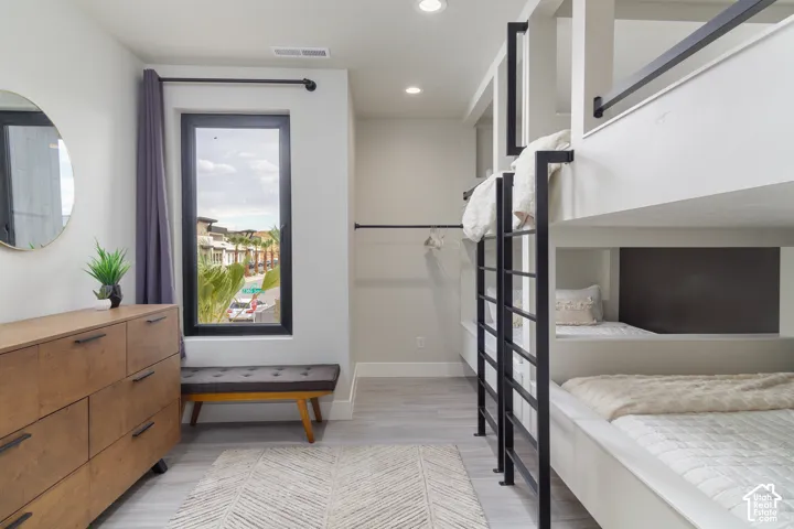Built-in bunk beds with black metal railing, recessed lighting, and wood-finish flooring