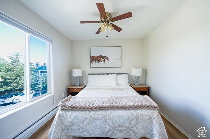 Bright room featuring wood-finish flooring, a large window, and a ceiling fan with integrated lighting