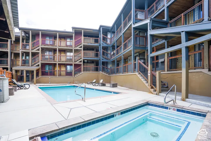 Outdoor pool and built-in hot tub with surrounding concrete patio