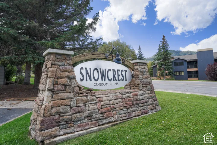 Stone-clad entrance sign with integrated lighting, surrounded by mature trees and manicured lawn