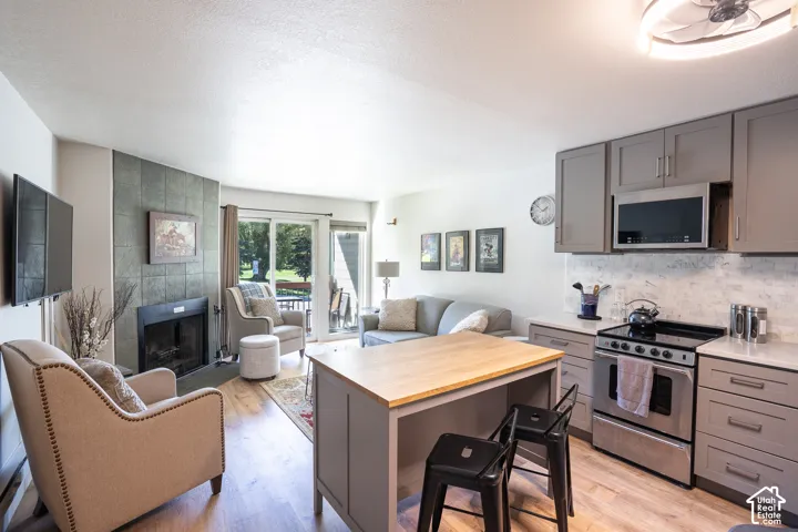 Open-concept living area featuring a stone-faced fireplace, wood-finish flooring, and a sliding glass door