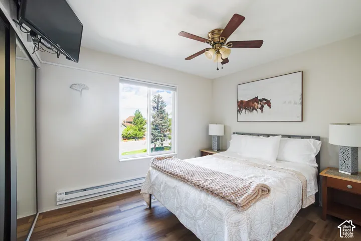 Wood-finish flooring, a ceiling fan with integrated lighting, and a large window providing natural illumination