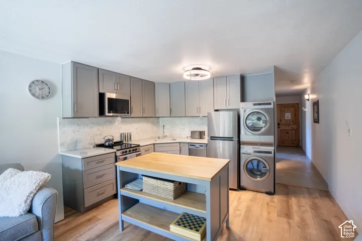 Contemporary kitchen with gray cabinetry, stainless steel appliances, and wood-finish flooring