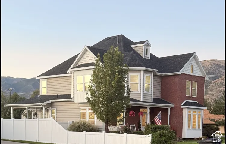 Traditional exterior featuring brick and siding finishes, multiple bay windows, a covered front porch, and a white picket fence