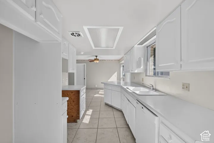 White cabinetry, built-in dishwasher, stainless steel faucet, tile flooring, and a ceiling fan