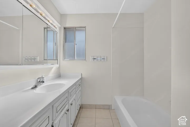 Vanity with integrated sink, chrome faucet, wall-mounted mirror, and overhead lighting