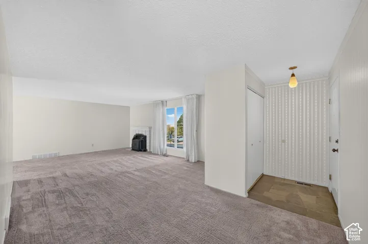 Expansive carpeted living area with a white brick fireplace