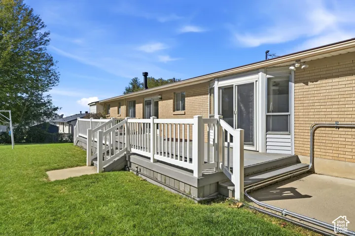 Expansive exterior deck with white railings, concrete patio, and a sliding glass door
