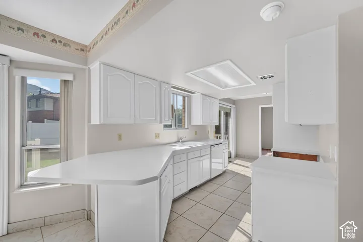 White cabinetry with recessed panel doors, tile flooring, and integrated white countertops