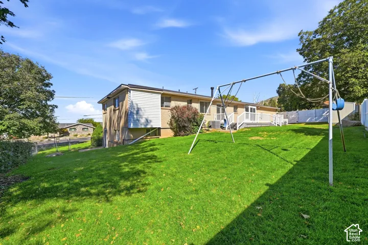 Expansive green lawn with a multi-level deck featuring white railings