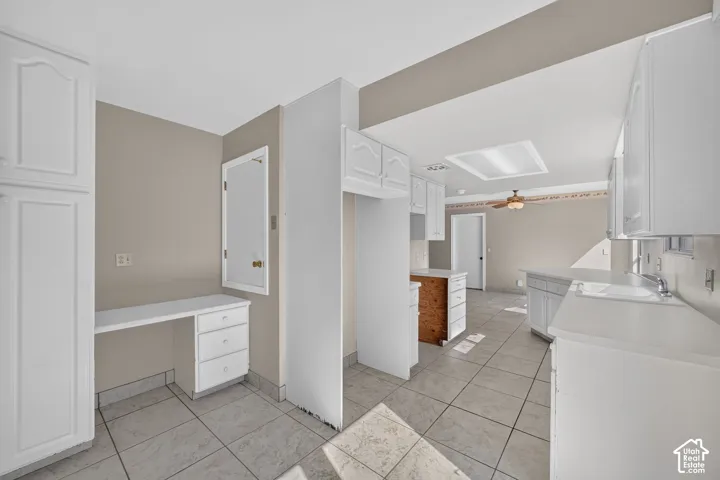 Kitchen featuring white cabinetry, tile flooring, built-in desk, and ceiling fan