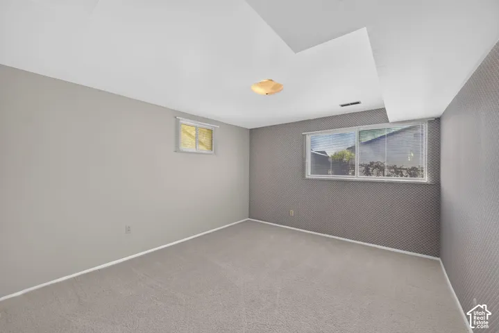 Neutral tone wall paint, textured accent wall, light-colored carpeting, recessed ceiling, and a flush mount light fixture