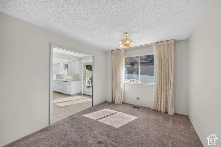 Recessed window with drapes, an overhead brass-finish chandelier, and wall-to-wall carpeting