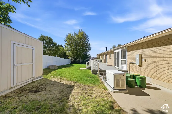 Expansive backyard featuring a manicured lawn, a white privacy fence, a detached shed, and a composite deck with white railings