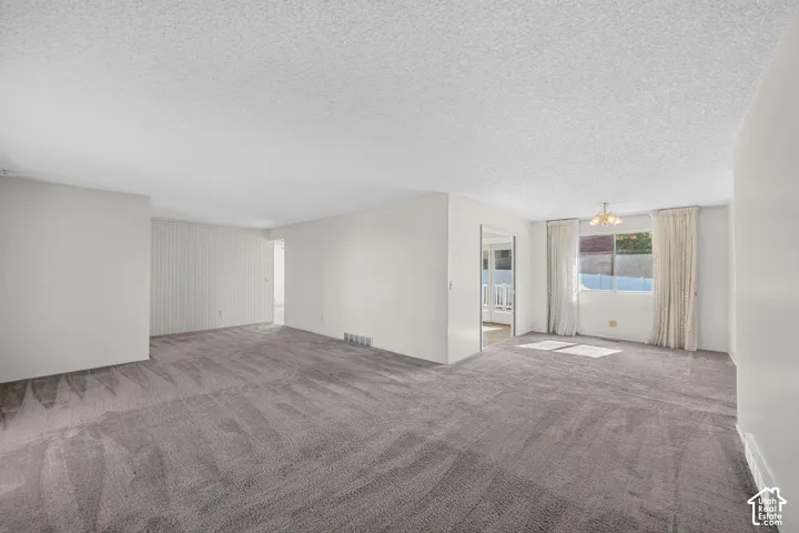 Spacious room with neutral wall tones and a textured ceiling