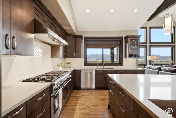 Kitchen featuring dark wood cabinetry, a large kitchen island with light-toned countertops, a herringbone tile backsplash, and stainless steel appliances