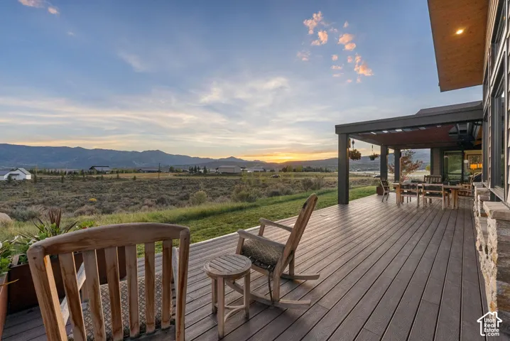Expansive composite deck featuring a covered patio area, recessed lighting, and stone exterior accents
