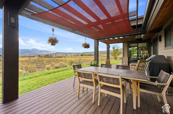 Expansive outdoor deck with a pergola, integrated shade sail, and dark wood-finish decking